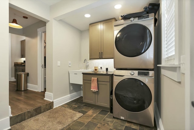 laundry area with sink, cabinets, and stacked washer and dryer