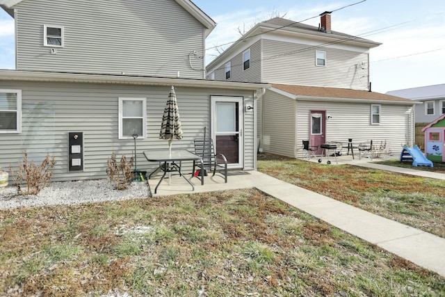 back of property with a lawn and a patio area