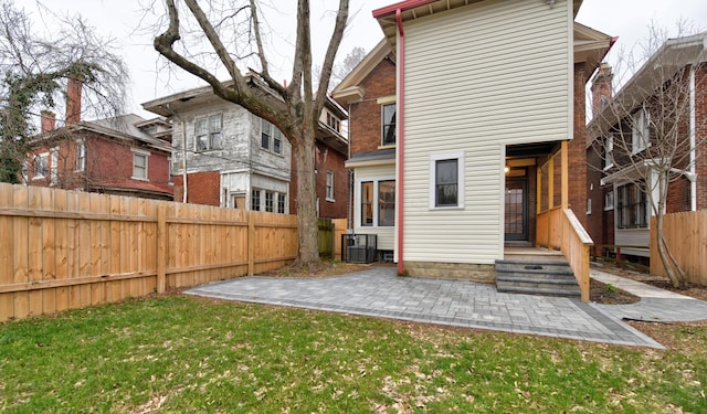 rear view of house featuring a lawn, cooling unit, and a patio