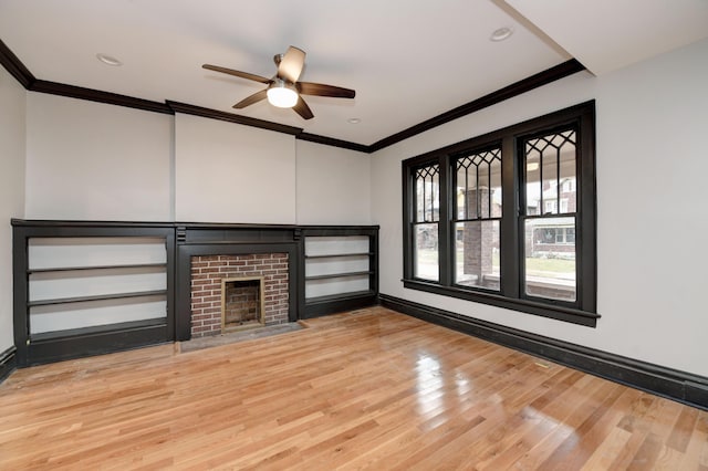 unfurnished living room with ceiling fan, crown molding, a fireplace, and light hardwood / wood-style flooring