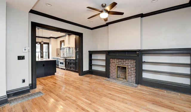 unfurnished living room with hardwood / wood-style floors, crown molding, sink, a brick fireplace, and ceiling fan