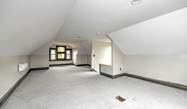 additional living space with a wall mounted AC and lofted ceiling