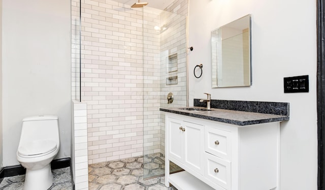 bathroom with vanity, toilet, and tiled shower