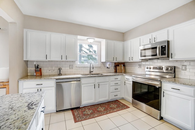 kitchen featuring sink, white cabinetry, backsplash, stainless steel appliances, and light stone counters