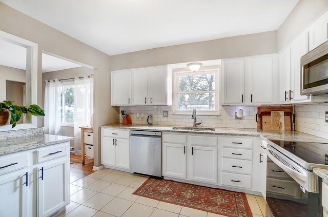 kitchen featuring stainless steel appliances, light stone countertops, sink, and white cabinets