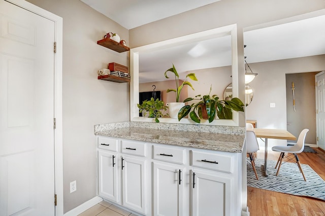 kitchen featuring light stone countertops, light hardwood / wood-style flooring, and white cabinets