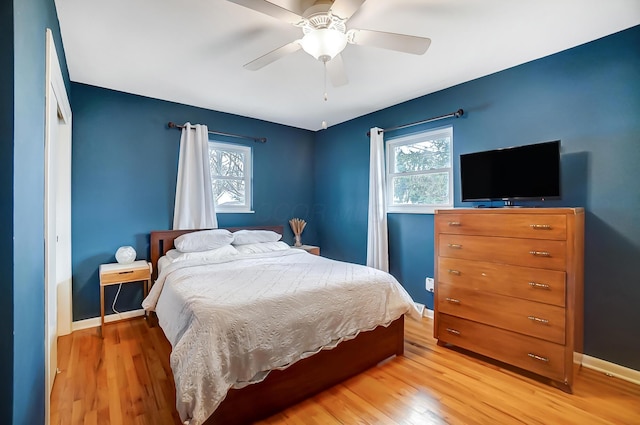 bedroom featuring multiple windows, hardwood / wood-style floors, and ceiling fan