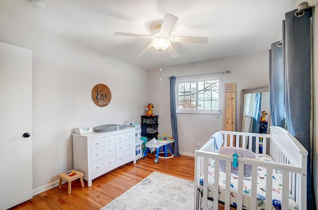 bedroom featuring a crib, light hardwood / wood-style flooring, and ceiling fan