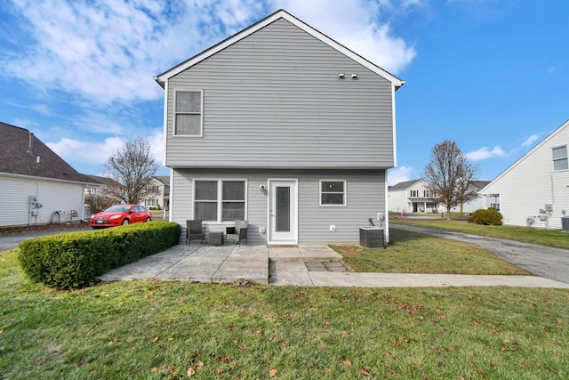 rear view of property with a lawn, a patio area, and central AC unit