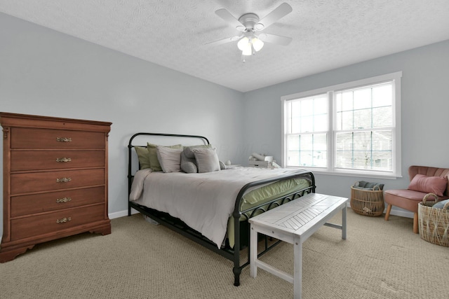 bedroom featuring a textured ceiling, light colored carpet, and ceiling fan