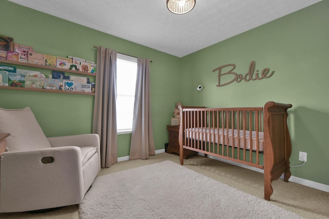 carpeted bedroom with a crib and a textured ceiling