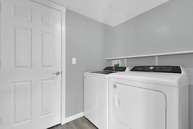 washroom with light hardwood / wood-style floors, independent washer and dryer, and a textured ceiling