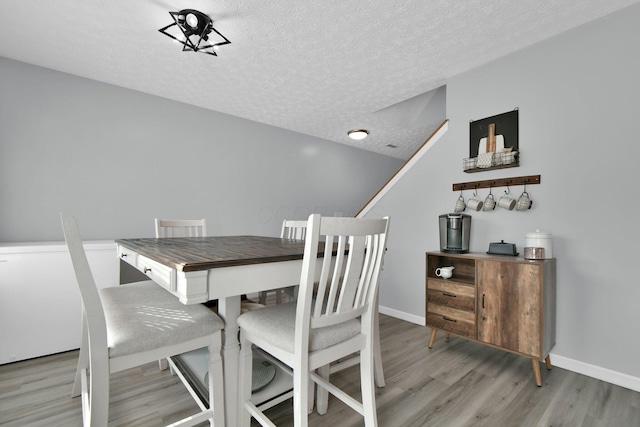 dining space featuring a textured ceiling and light wood-type flooring