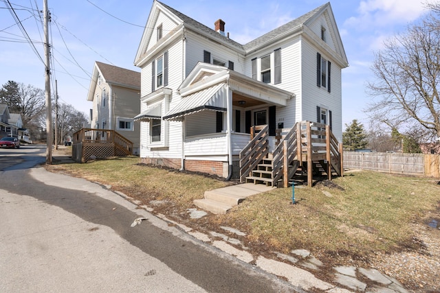 american foursquare style home featuring a chimney, fence, and a front yard