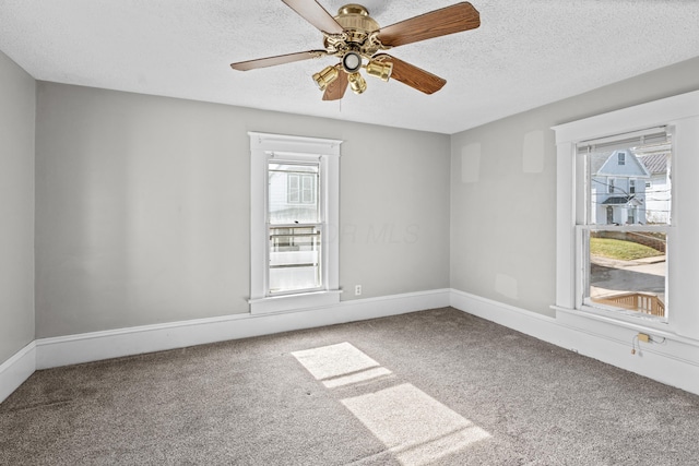 spare room featuring carpet floors, a ceiling fan, baseboards, and a textured ceiling