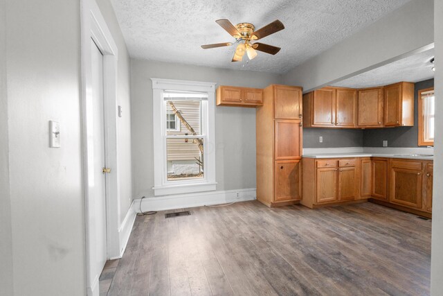 kitchen with dark wood-style flooring, a sink, visible vents, baseboards, and light countertops