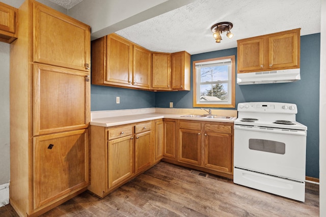 kitchen featuring visible vents, white range with electric cooktop, wood finished floors, under cabinet range hood, and a sink