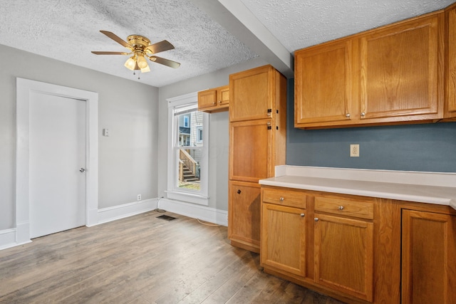 kitchen with brown cabinetry, light countertops, and wood finished floors