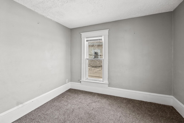 empty room with carpet floors, baseboards, and a textured ceiling