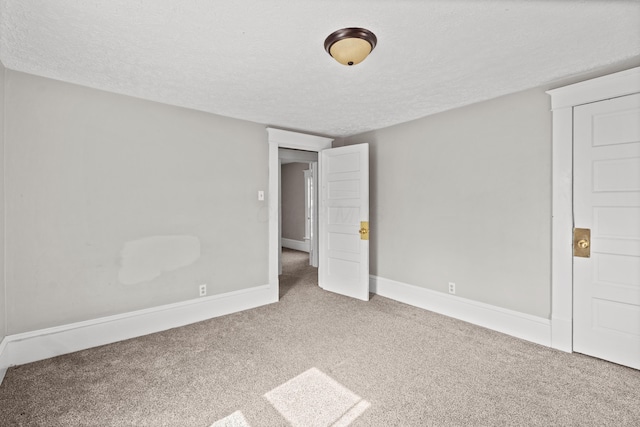 unfurnished bedroom with a textured ceiling, baseboards, and carpet flooring