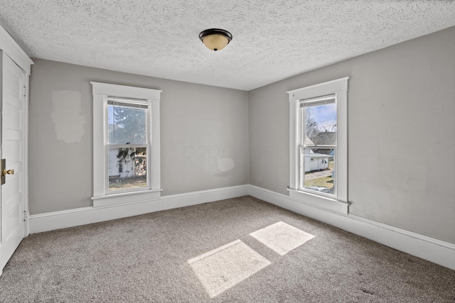 carpeted empty room with a textured ceiling and baseboards