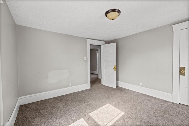 unfurnished bedroom with carpet, a textured ceiling, and baseboards