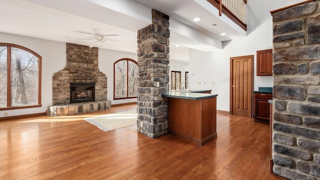 bar featuring ceiling fan, a large fireplace, and dark wood-type flooring