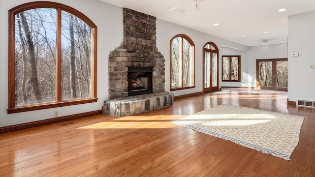 unfurnished living room featuring a large fireplace, light hardwood / wood-style floors, and ceiling fan