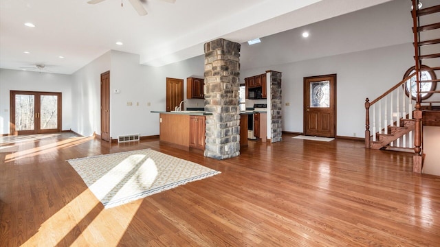 unfurnished living room with french doors, sink, ceiling fan, ornate columns, and wood-type flooring