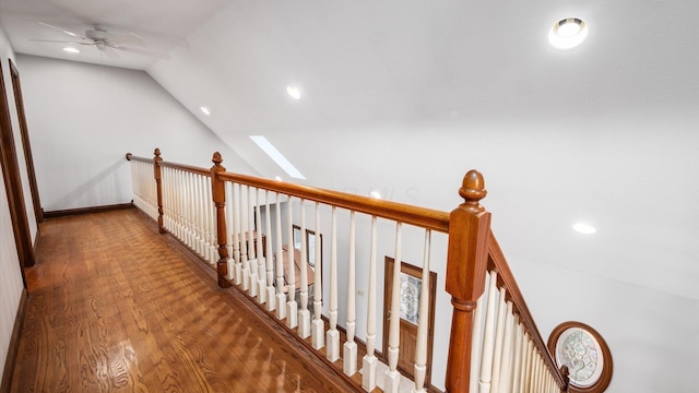 hallway featuring vaulted ceiling with skylight and hardwood / wood-style flooring