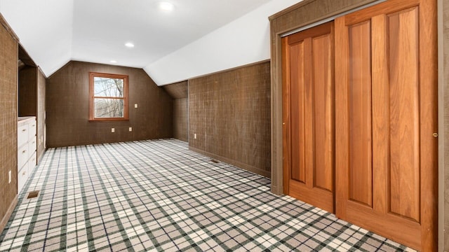 bonus room featuring vaulted ceiling and wood walls