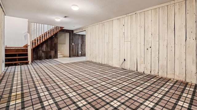 basement with wooden walls and a textured ceiling