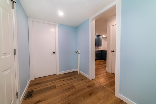 hall with a barn door, hardwood / wood-style floors, and a textured ceiling