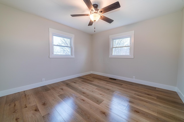 spare room with a wealth of natural light, ceiling fan, and light hardwood / wood-style floors