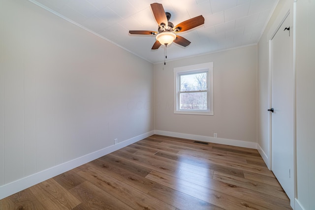 unfurnished room with ceiling fan, light wood-type flooring, and crown molding