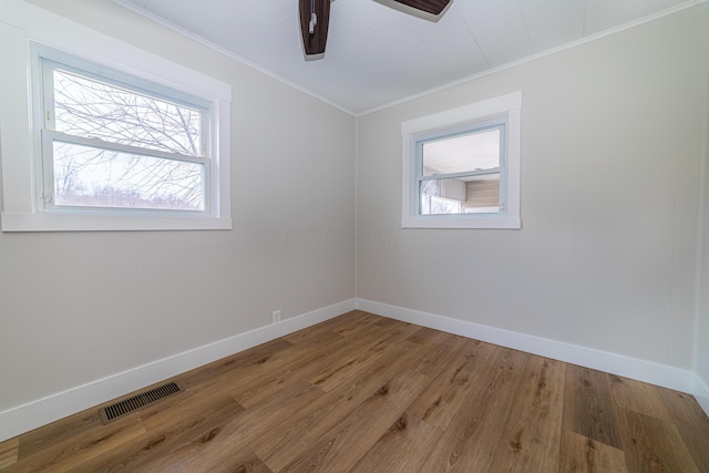 spare room with crown molding, hardwood / wood-style floors, ceiling fan, and a healthy amount of sunlight