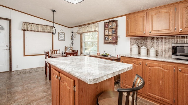 kitchen featuring pendant lighting, backsplash, ornamental molding, a textured ceiling, and a kitchen island