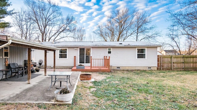 rear view of house with a wooden deck, a yard, and a patio