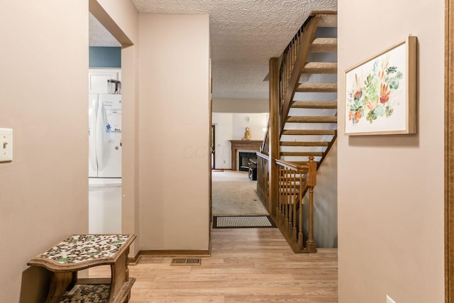 hallway featuring light wood-type flooring and a textured ceiling