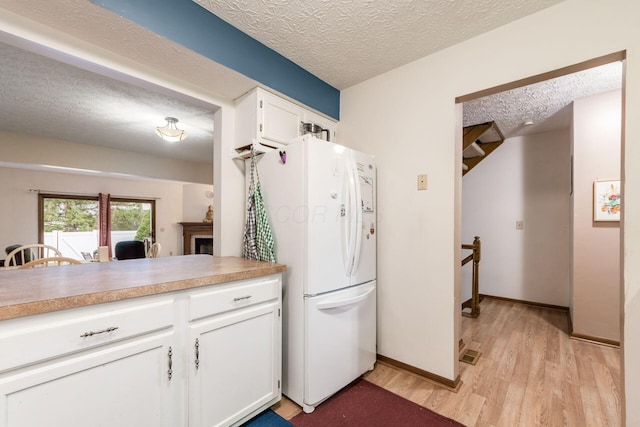 kitchen with white cabinets, white refrigerator, and a textured ceiling