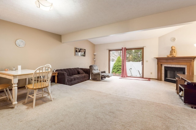 carpeted living room with lofted ceiling with beams and a tile fireplace