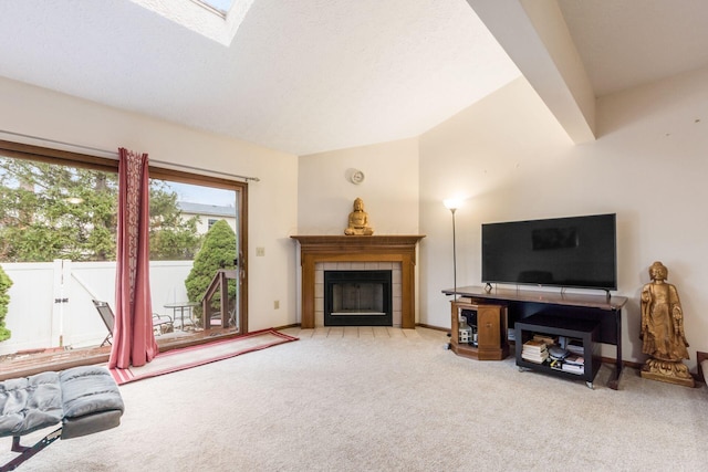 living room featuring vaulted ceiling with skylight, light colored carpet, and a tile fireplace