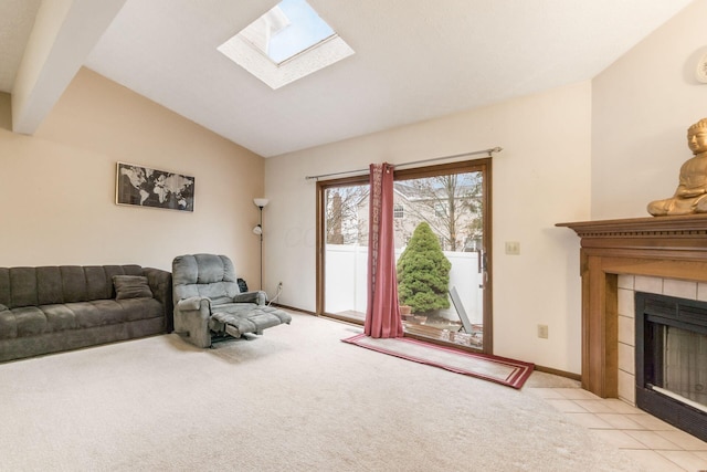 living room with vaulted ceiling with skylight, light colored carpet, and a tiled fireplace