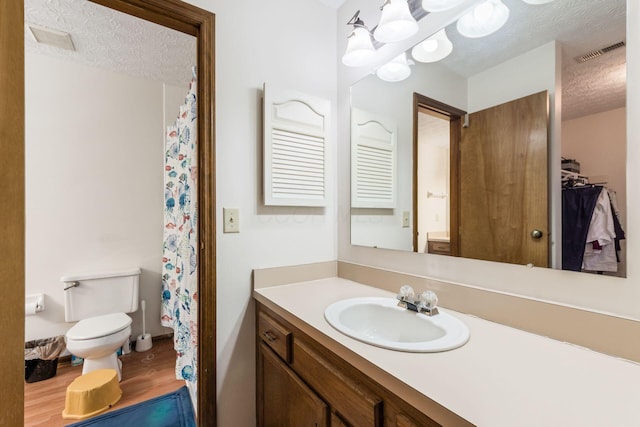 bathroom with vanity, wood-type flooring, a textured ceiling, and toilet