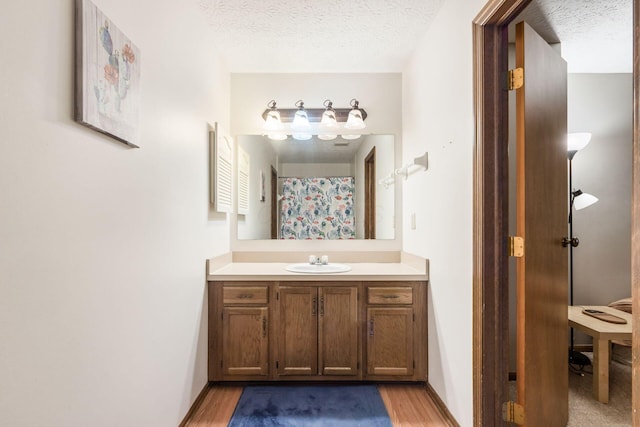 bathroom featuring vanity, wood-type flooring, and a textured ceiling