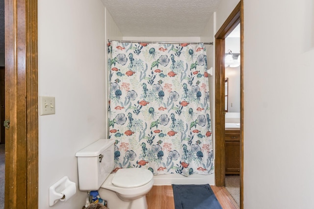 bathroom with hardwood / wood-style floors, vanity, toilet, and a textured ceiling