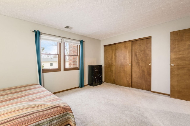 bedroom with a closet, light colored carpet, and a textured ceiling