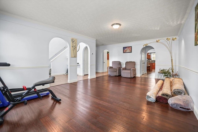 exercise room with hardwood / wood-style floors, a textured ceiling, and crown molding