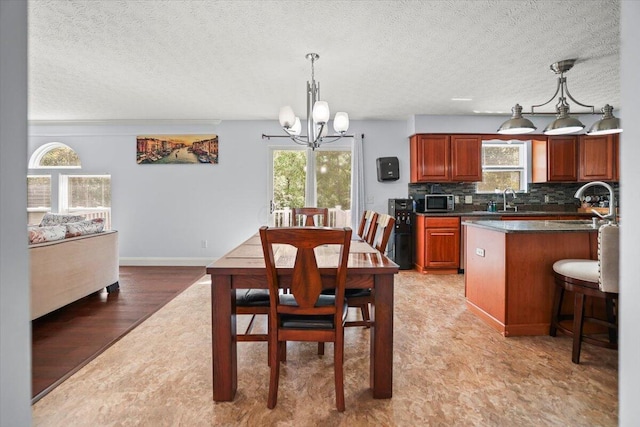 dining room featuring a textured ceiling, light wood-type flooring, sink, and a chandelier