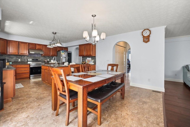 dining space featuring a textured ceiling, a notable chandelier, and sink